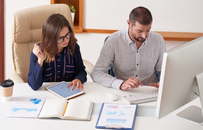 Financial managers working with charts and reports at big office table